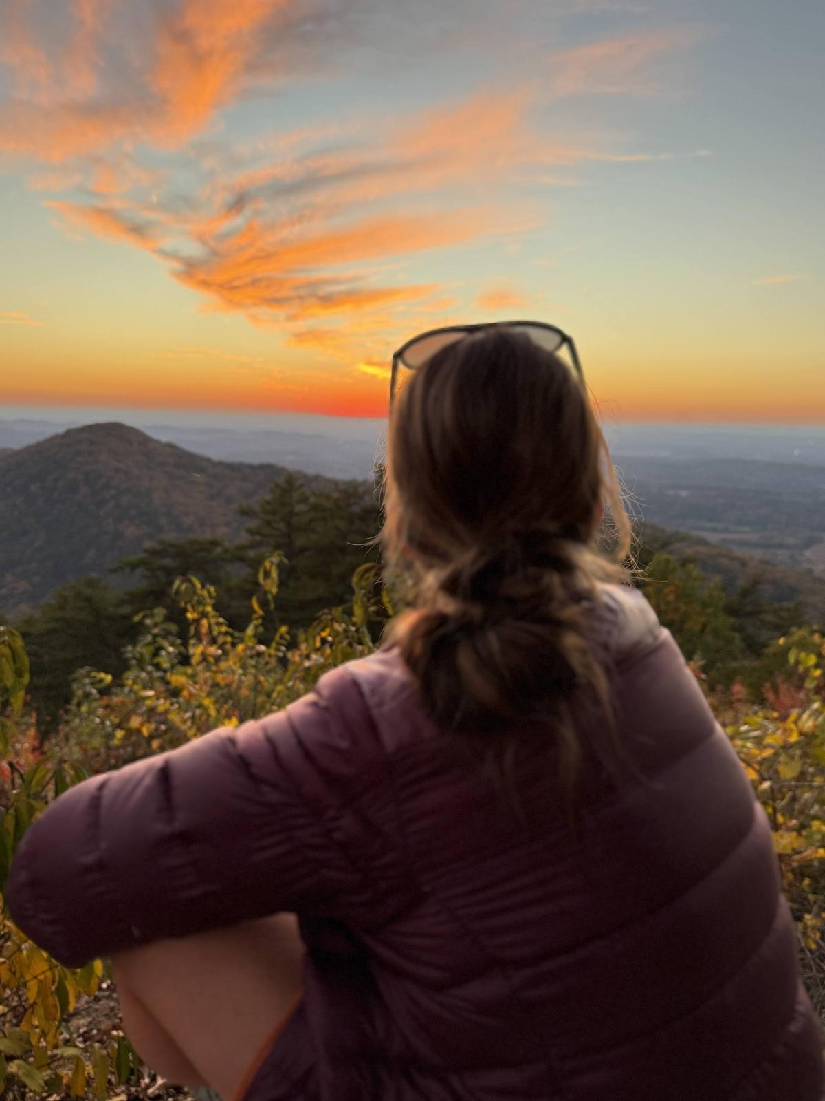 Michelle Walraven sitting on a mountain overlook at sunset